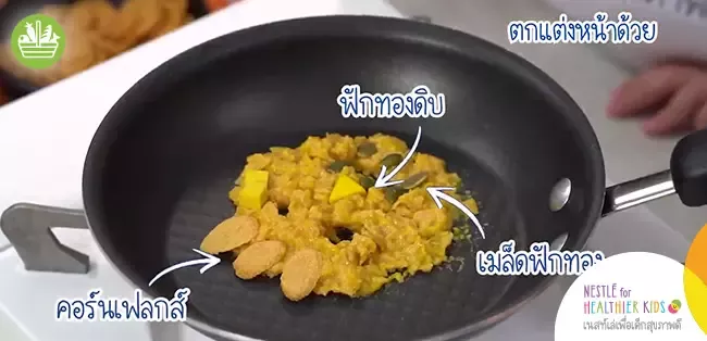 3. ตกแต่งหน้าคุ้กกี้ด้วยชิ้นฟักทองดิบ เมล็ดฟักทอง และ เนสท์เล่ ซีเรียล โกลด์ คอร์นเฟลกส์ ตามชอบ และนำกระทะตั้งไฟใช้ไฟปาน